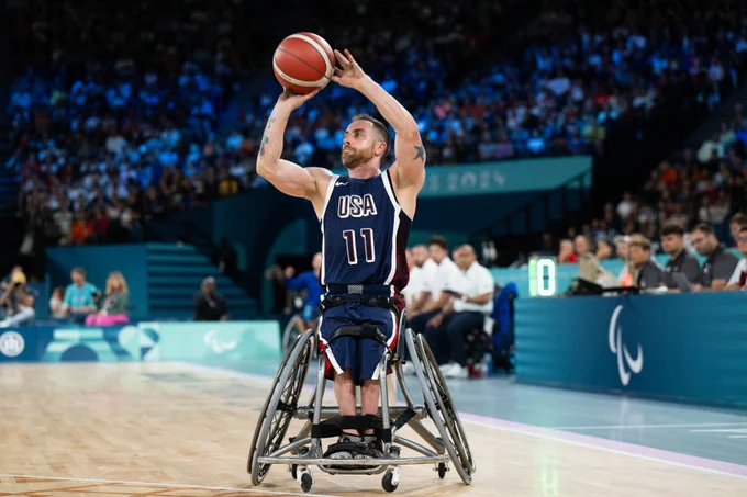 A person shooting a basketball while wearing a jersey that says USA 11.