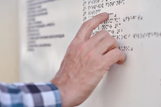 A person reading a braille building directory.