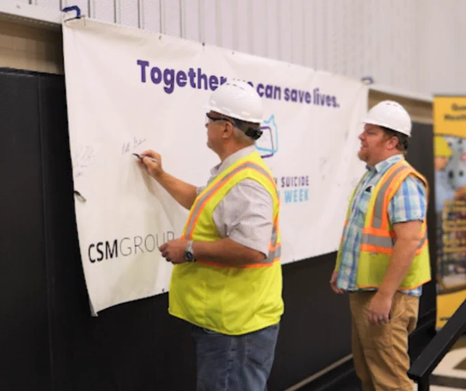 MIOSHA construction safety consultants sign a Suicide Prevention Week banner during MIOSHA's constriction suicide awareness event in Kalamazoo on Sept. 11, 2024
