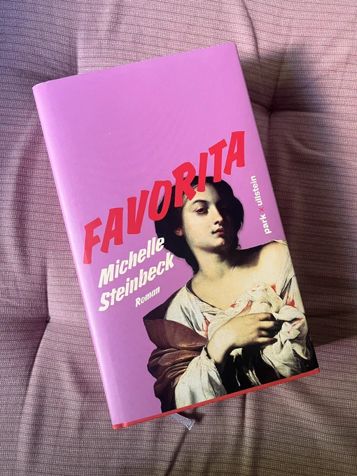 A pink book cover on a pale pink cushion.