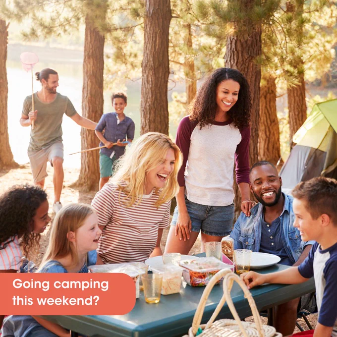 Family camping trip in the woods. Three kids and three adults gathered around a table