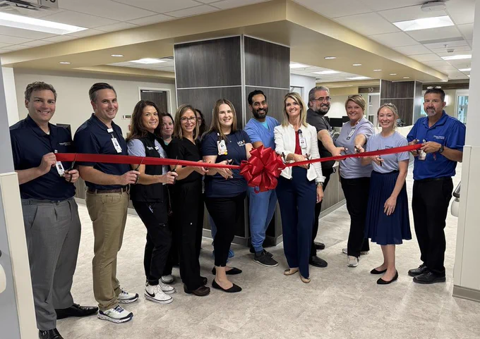 Colleagues with a red ribbon for the ribbon cutting