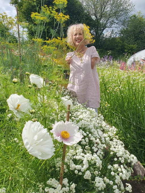 A photo of Sue Kent surrounded by white flowers