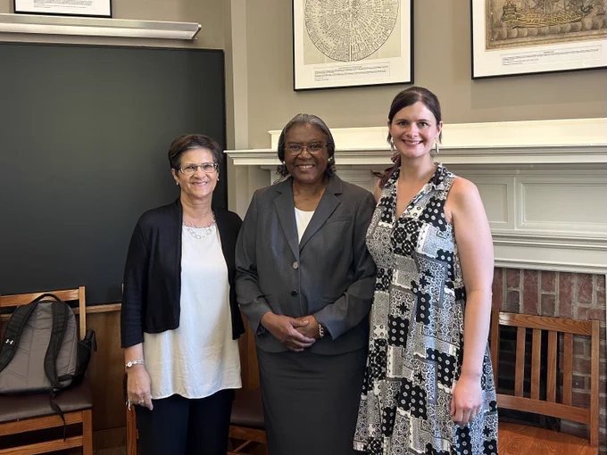 Three women stand together side by side smiling at the camera