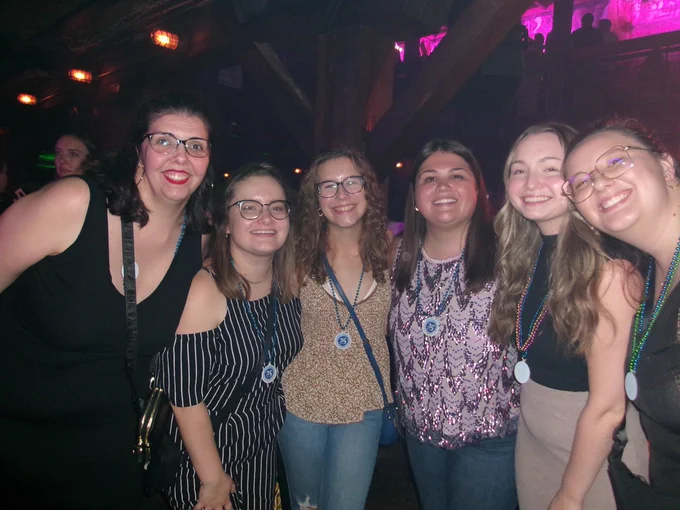 6 women smile for the camera in a dark room