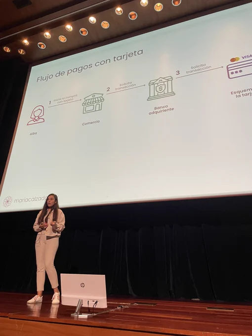 Foto de María en el escenario del auditorio, con su presentación de fondo