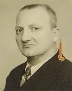 Vintage passport-style photo of a man with a solemn expression, wearing a formal suit and tie.
