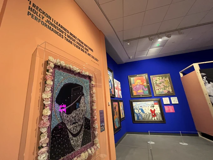 Exhibit displaying artworks set against a bright orange wall and a blue wall. 