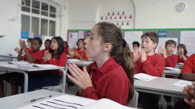 Children reading aloud, and clapping the word, to explore language of reading in the classroom. 