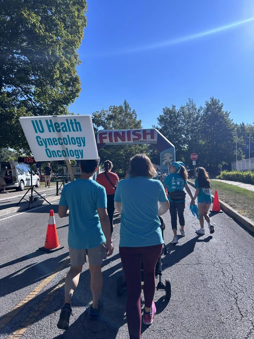 Walkers approach the Finish balloon arch while carrying a sign reading IU Health Gynecology Oncology.