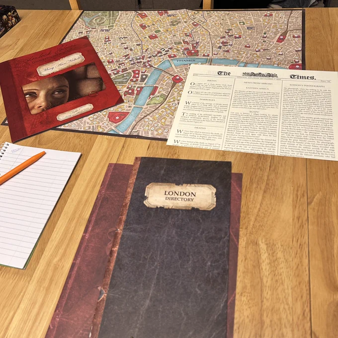 Photo of the game set up for ‘Sherlock Holmes: Consulting Detective’. Showing a directory and a map of London, a newspaper and a booklet for the case of Mary Ann Nichols