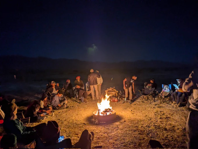 A campfire in the desert with people around 