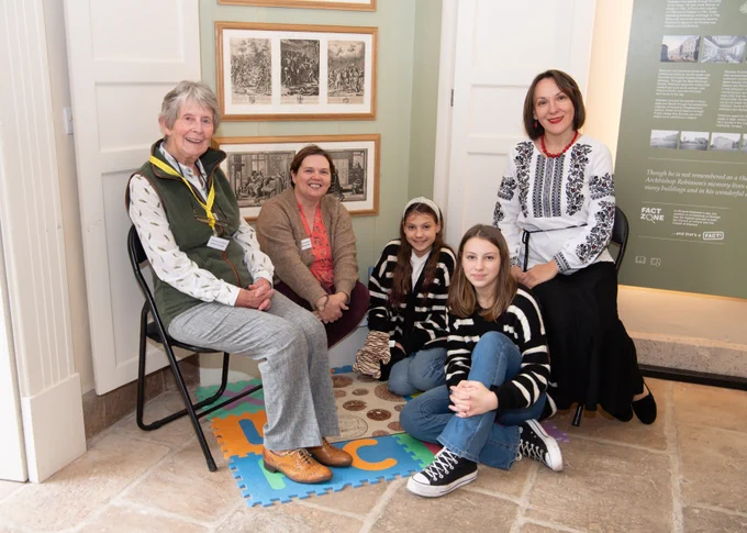 Two members of staff sitting in a museum room with two young girls and their mother. | Library volunteers Ursula Monaghan and Zena Dawson welcomed Ukrainian family members Inna Shynkevich and her daughters Sofia and Valeriia.