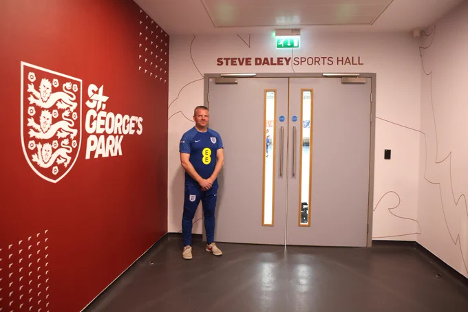 Steve Daley poses for a photo outside the entrance to the Steve Daley Sports Hall at St. George's Park