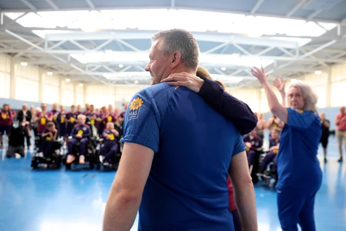 Players and staff applaud Steve Daley as he enters the Steve Daley Sports Hall at St. George's Park