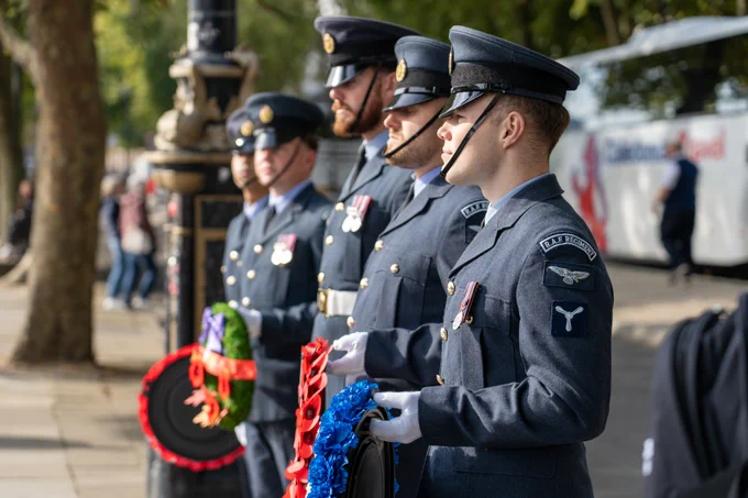 Five RAF Servicepeople standing in a line holding wreaths.