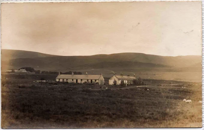 two rows of cottages at right angles in a near treeless landscape. low rolling hills in distance. 