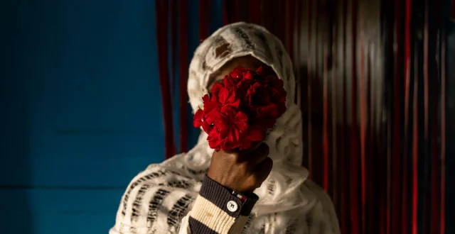 donna con velo copre il suo viso con un mazzo di fiori rossi - World Press Photo
