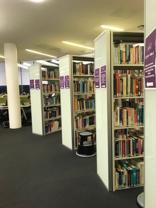 Library shelves, with study desks in the distance