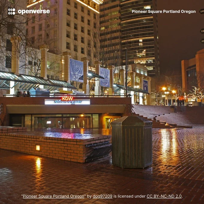 Nighttime view of Pioneer Square in Portland, Oregon, featuring wet pavement reflecting city lights.