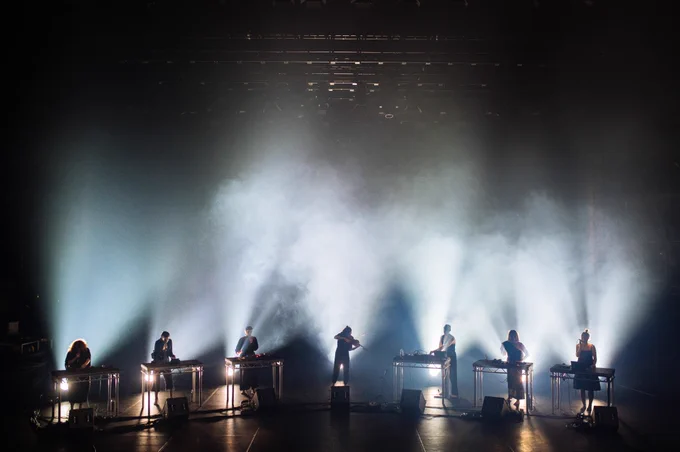 A group of musicians performing on a dimly lit stage with spotlights.