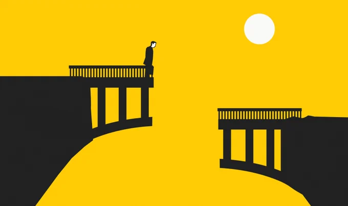 A man stands at the end of a broken bridge, he looks over the edge but cannot cross.