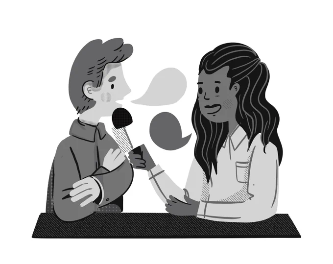 
This is a grayscale illustration showing two people sitting at a table. One person, on the left, is speaking into a microphone held by the other person, on the right. The person on the left has short hair and is wearing a jacket. The person on the right has long hair and is wearing a collared shirt, smiling as they conduct what appears to be an interview. Both individuals have speech bubbles above their heads, indicating conversation or dialogue.
