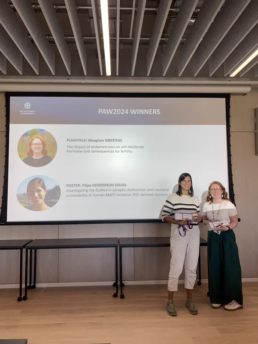 A picture of Maeghan Griffin and Filipa Henderson Sousa in front of a slide with their names and pictures, announcing they won best flash talk and best poster presentation at todays Bioquarter Postdoc symposium.