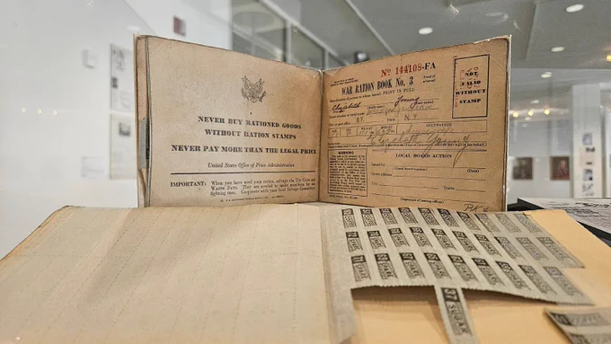 Display of historical ration books with filled ration stamps, exhibited in a museum setting.