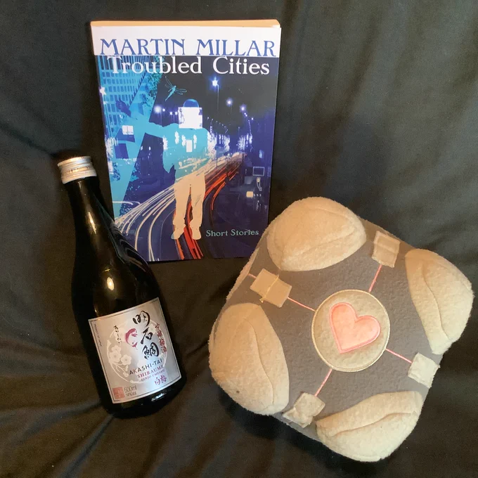 Martin Millar's book of short stories, a companion cube and a small bottle of umeshu, Japanese plum liqueur.