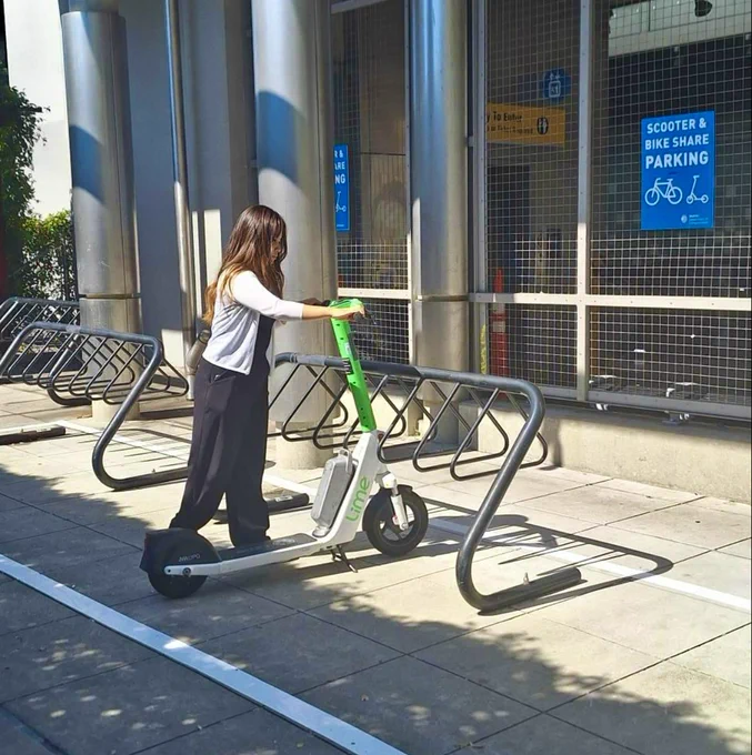 A person parks a Lime scooter at a Scooter and Bike Share Parking corral on Capitol Hill.