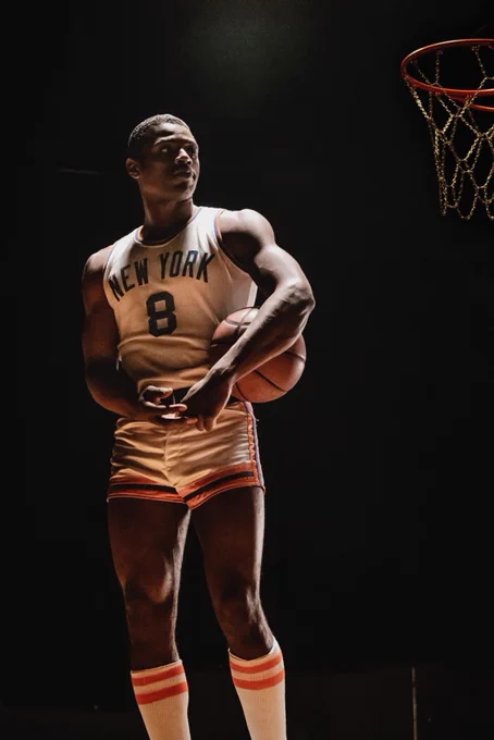Everett Osborne as Nathaniel "Sweetwater" Clifton. Osborne stands beside a basketball hoop, wearing a New York Knicks jersey, Number 8. A basketball is tucked under his left arm, and he is looking up toward the basket. 