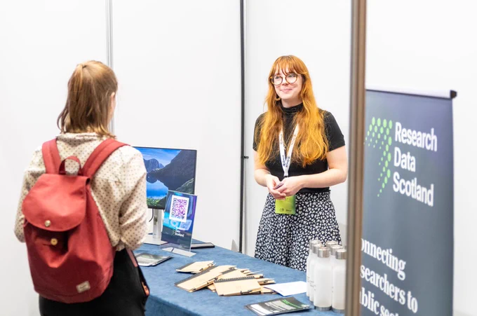 woman stood at Research Data Scotland speaking to stand visitor