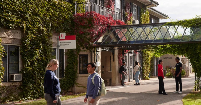 Mutilple groups of diverse students standing in front of the Glendon Manor, a beautiful building covered in greenery.