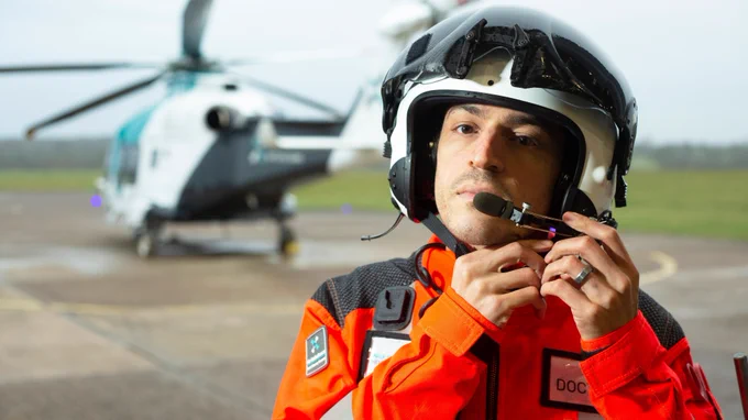 A pilot adjusts his helmet, shortly before boarding an air ambulance to fly to an emergency.