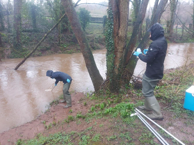 two people collecting river samples