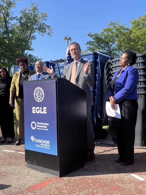 EGLE Director Phil Roos stands at podium speaking to audience at the press conference and the first residential cart distribution in Flint, in and near Rollingwood Park.