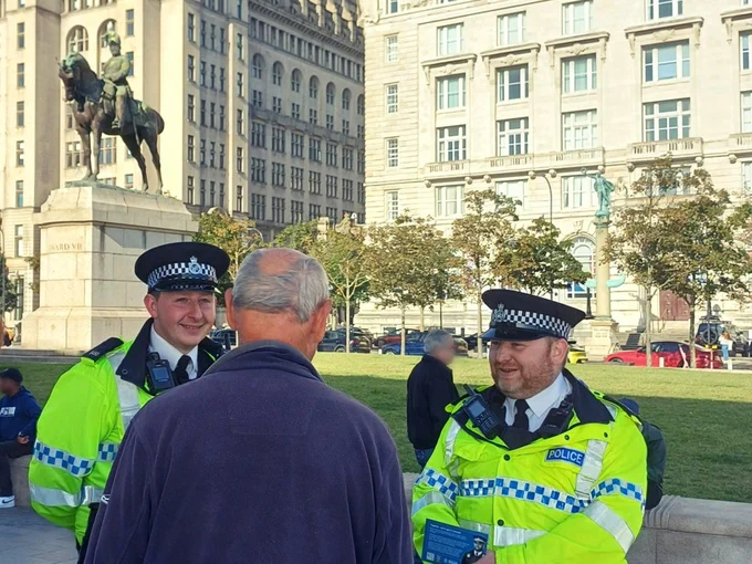 Project Servator officers speaking with member of the public at Pier Head, Liverpool, opposite the Royal Liver Building.