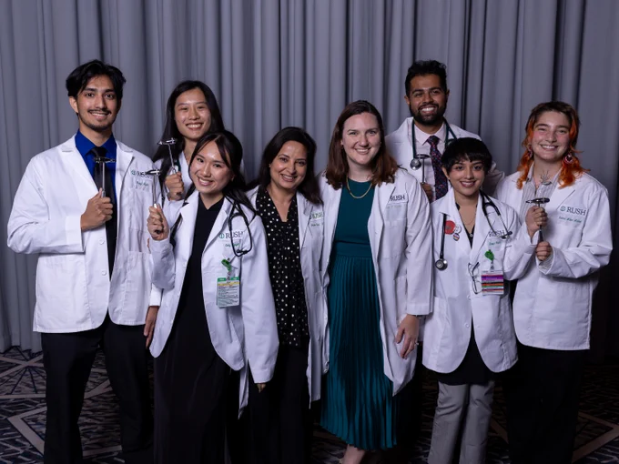 Group of eight medical students in white coats, smiling for the camera at the white coat ceremony. 