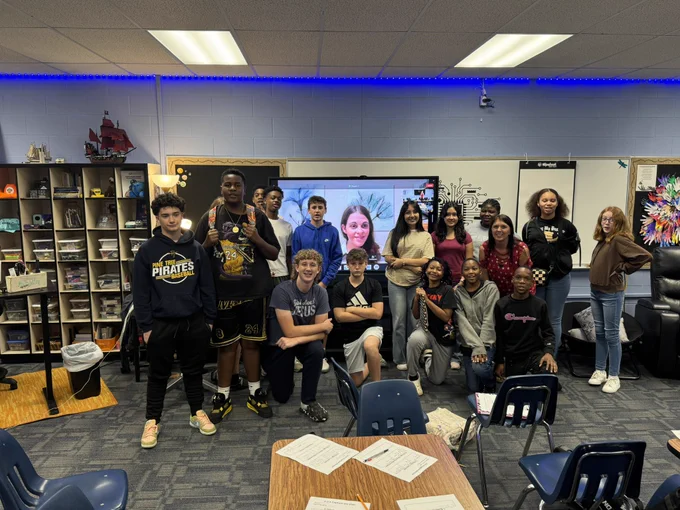 Students standing around an interactive board with Jordyn zooming in.