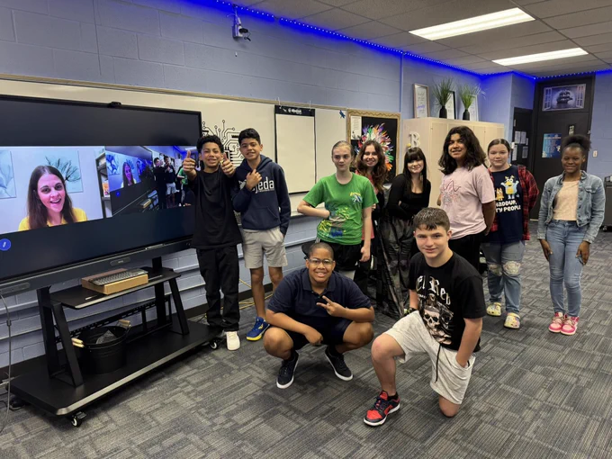 Students standing around an interactive board with Jordyn zooming in.