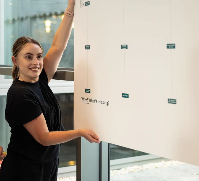 Person smiling and interacting with an interactive display titled "Why? What's missing?" at SDinGov