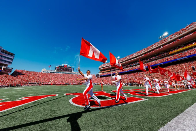 The Husker Cheer Squad runs on the field holding flags that spell "Nebraska"