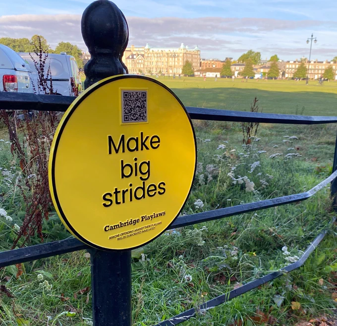 A yellow plaque, affixed to railings, reads 'Make big strides'