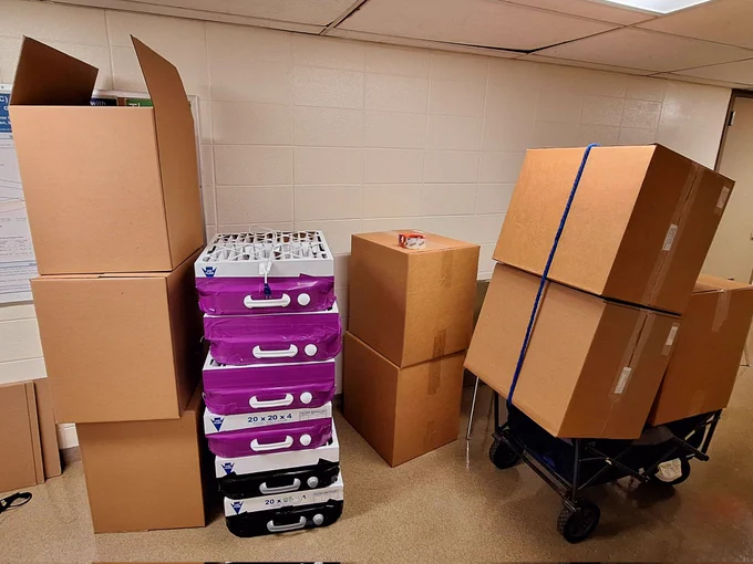 Prep scene for mailing the Kits, boxes and supplies piled high. 