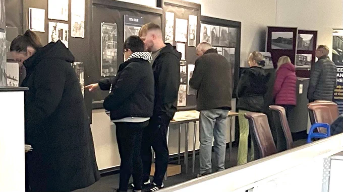 People looking at the old photographs exhibited on the walls of Colne Library