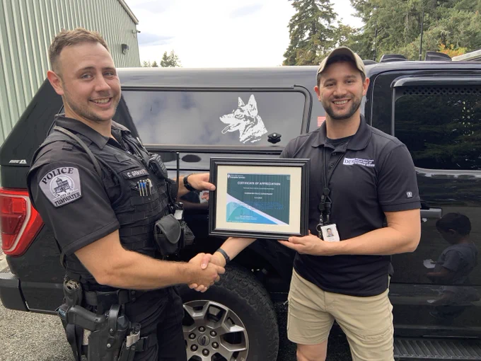 DES Surplus Operations' Matt Domenech presenting a certificate of appreciation to TPD's Officer Grimmett.