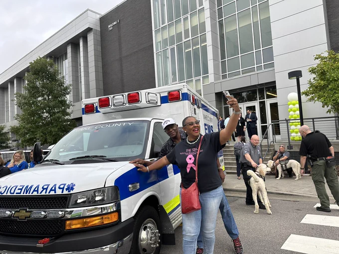 A man and woman taking a selfie in front of a Wake County Ambulance