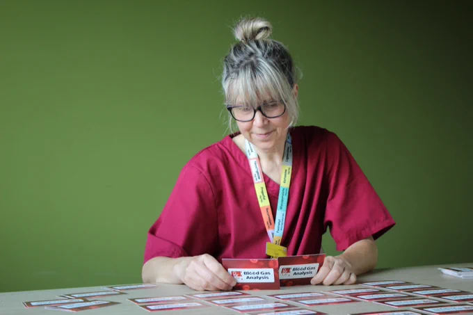 An image of a woman in pink scrubs playing the PAIR UP game at a table