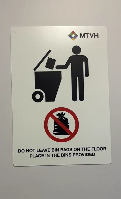 A poster from MTVH. The text reads “do not leave bags on the floor. Place in the bins provided”